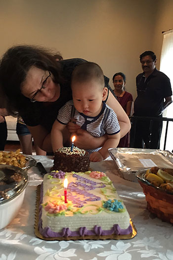 photo of Catalina holding baby over cake with candle